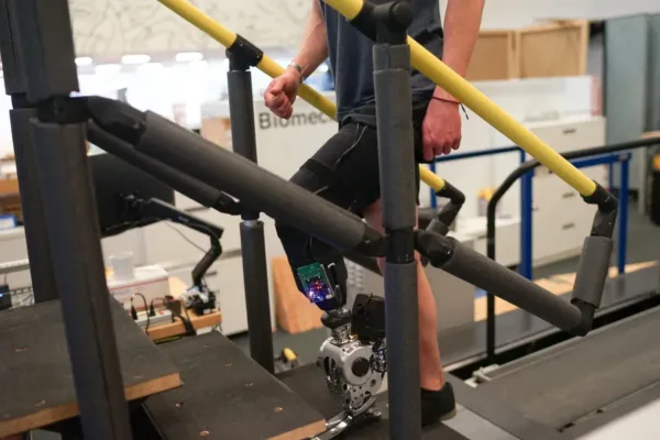 man with bionic leg climbing a set of stairs in a lab setting