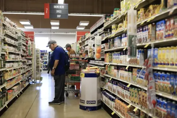 Man stands in aisle of grocery store looking a items on shelves